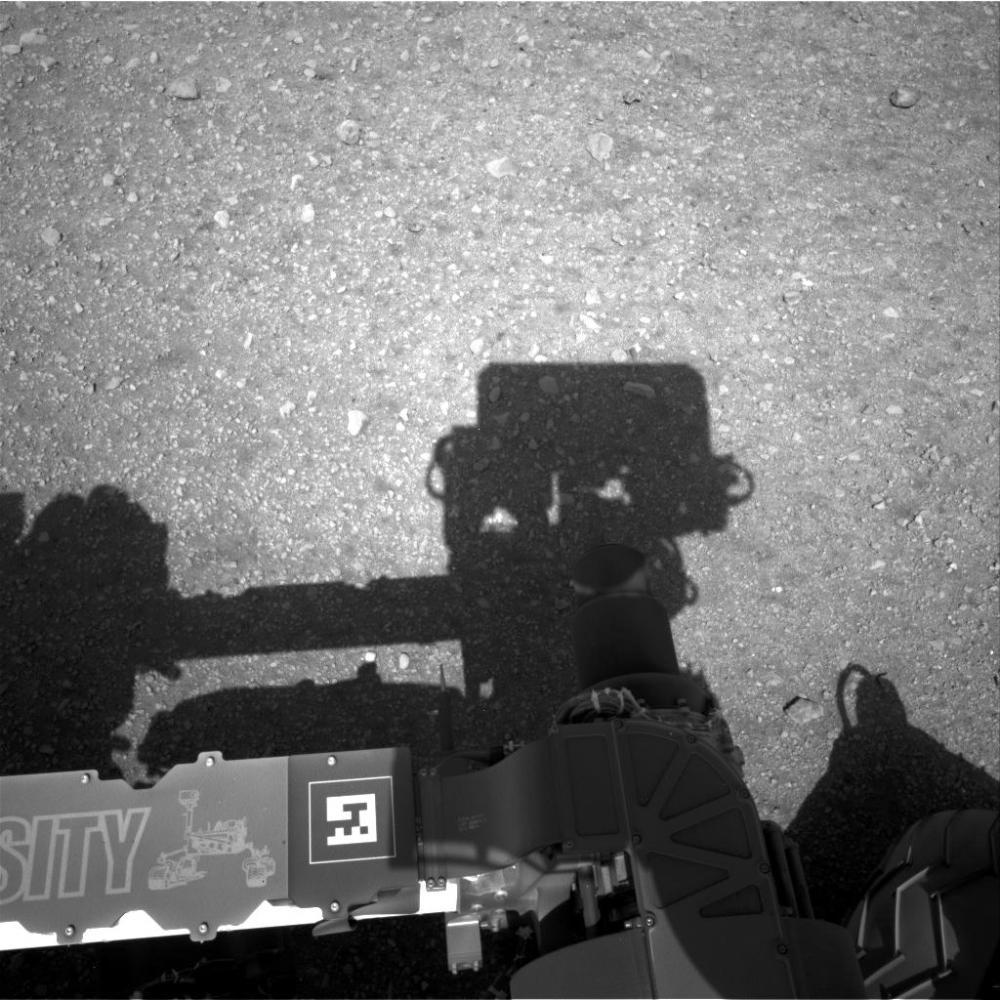 Ombre de Chemcam situé en haut du mat du rover. On aperçoit également Le bras robotique au premier plan. (Credit : NASA/JPL-Caltech)
