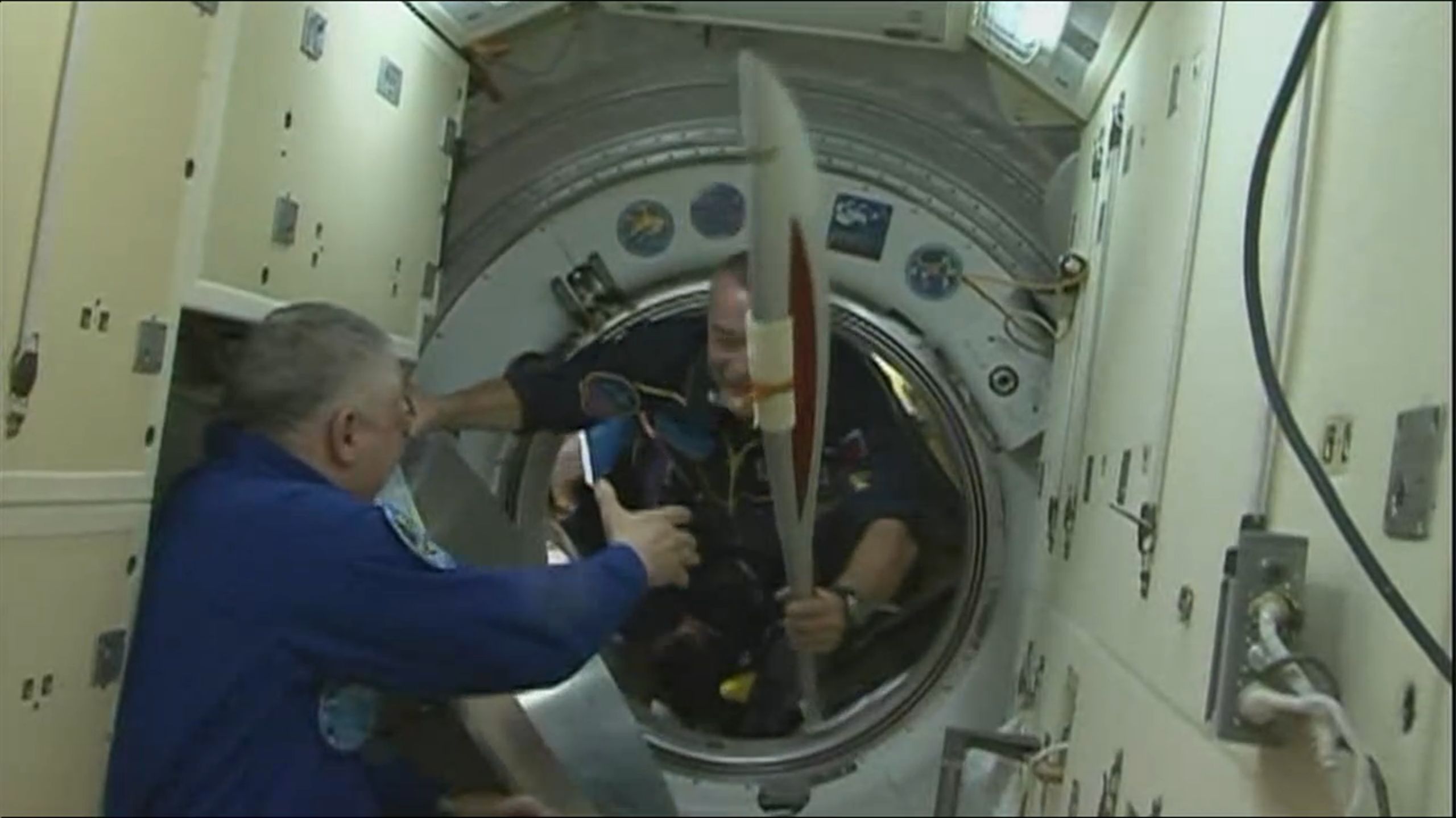 Entrée de Mikhail Tyurin transportant la torche à bord de la Station (Crédits : NASA TV)